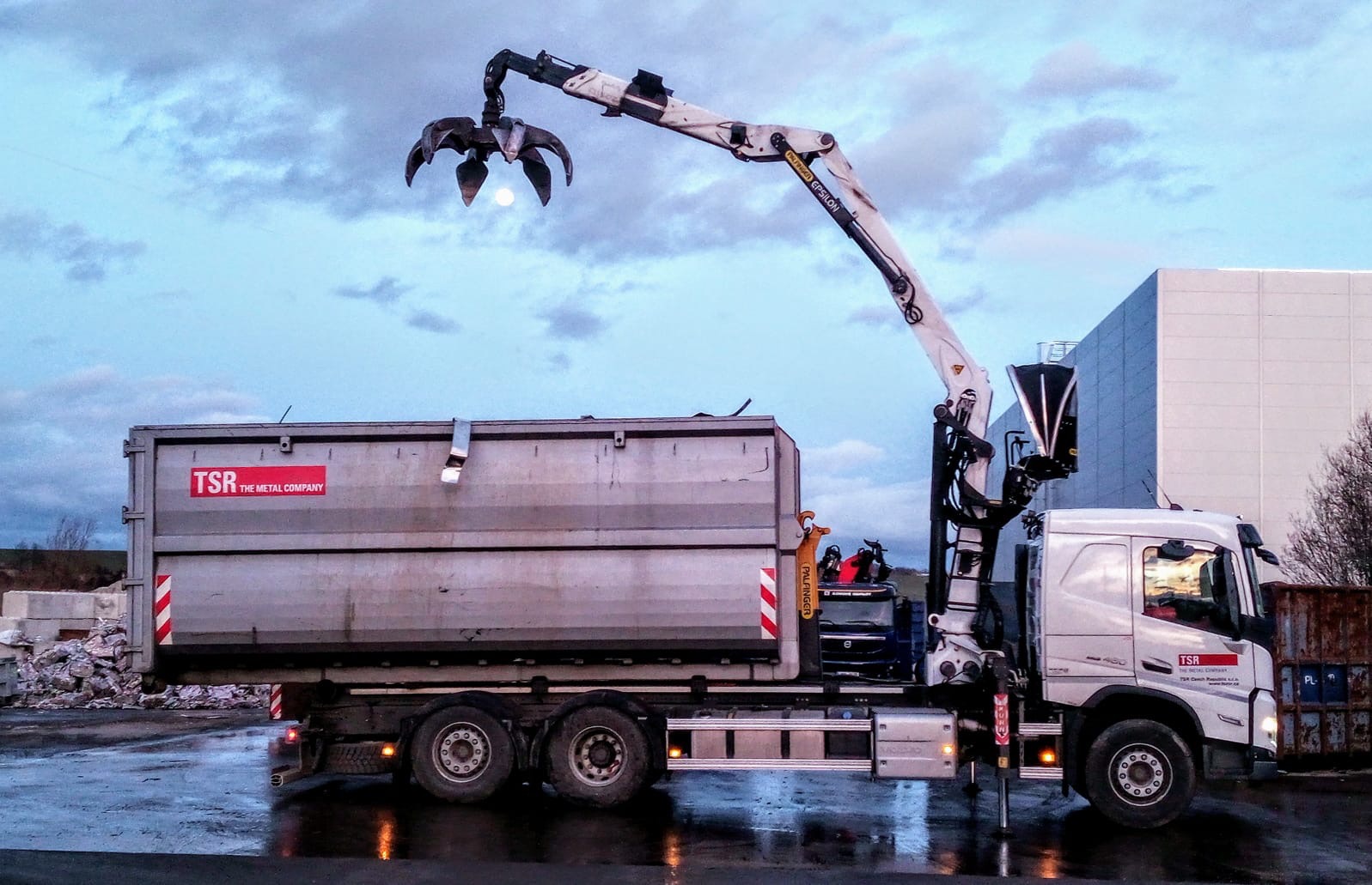 Nákladní auto TSR s hydraulickou rukou nakládá kontejner s kovem